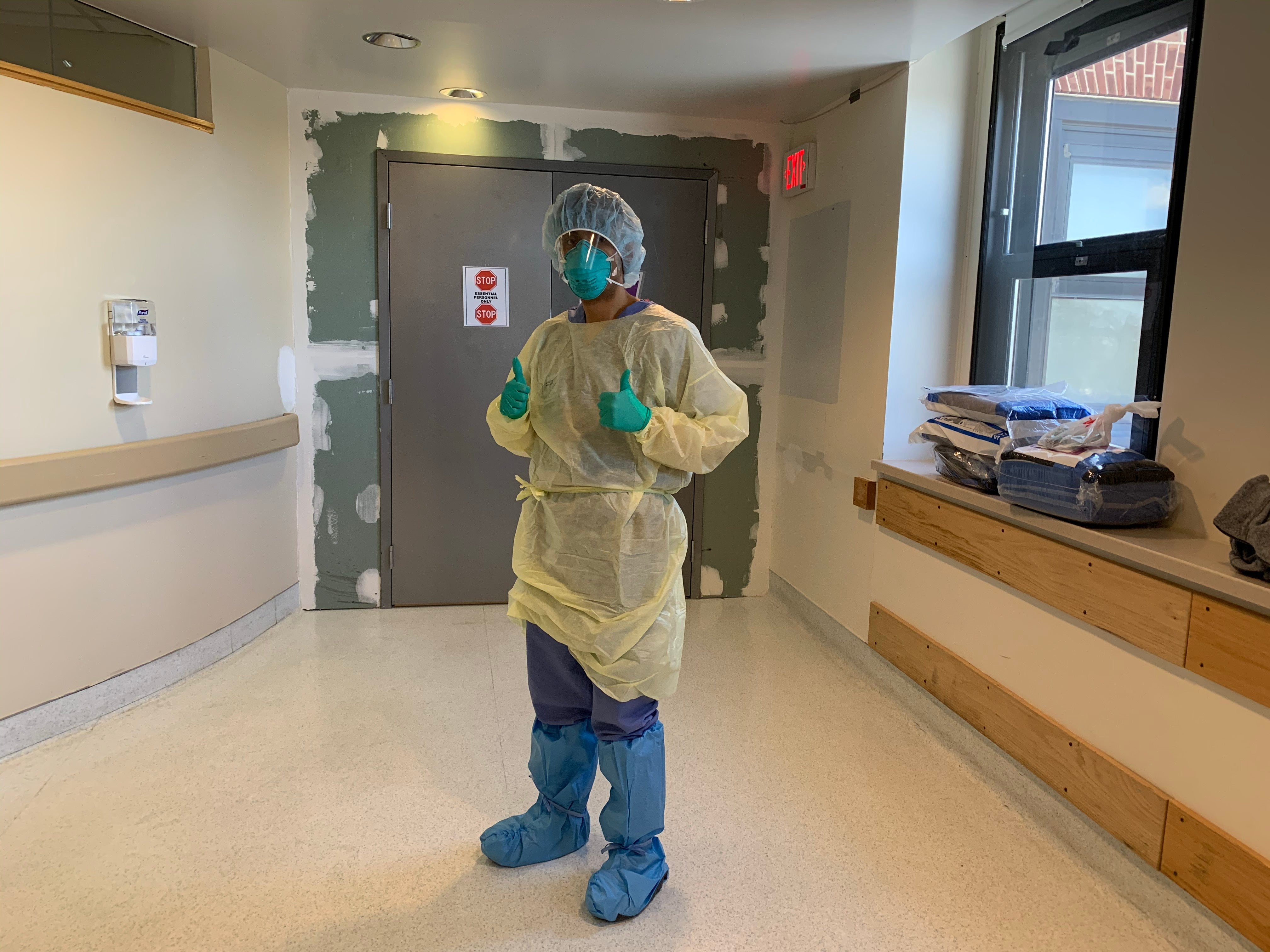 David Sanchez in his scrubs, gloves, and face mask in a hallway at Brigham and Women's hospital