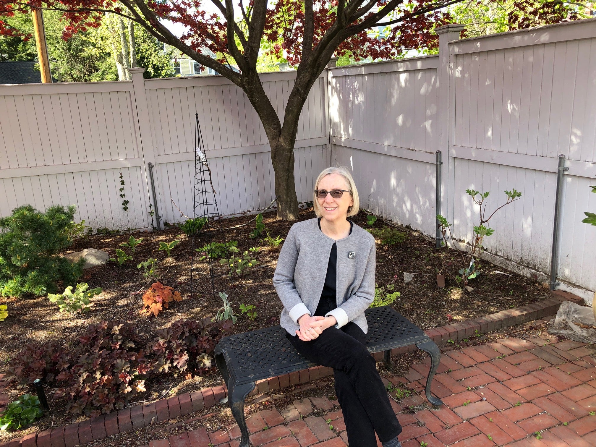 Karen Emmons sitting on a bench in her backyard.