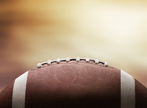 Close-up of football with yellow/brown background.