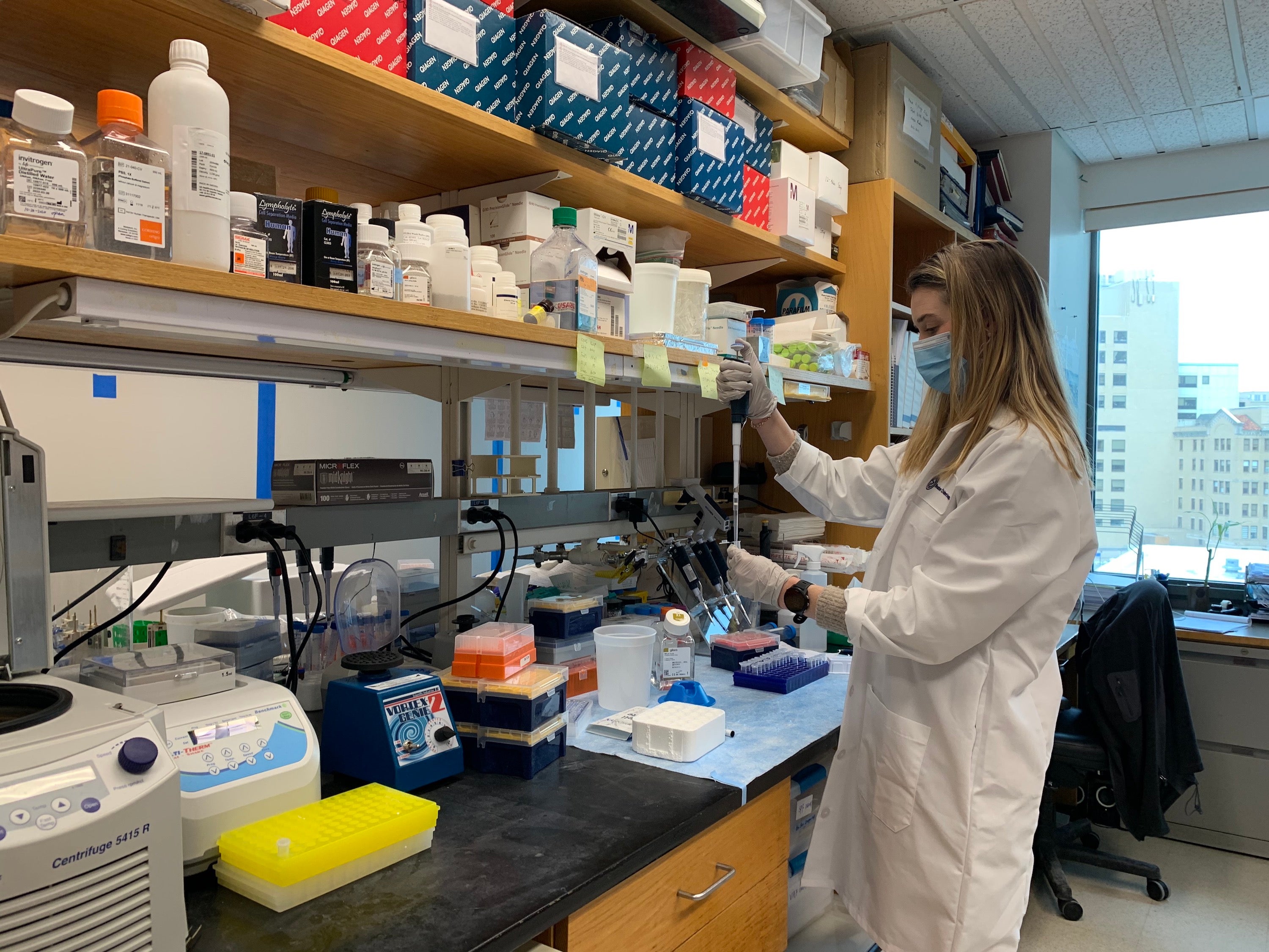 Lauren Collen working in the lab with white coat and mask on.