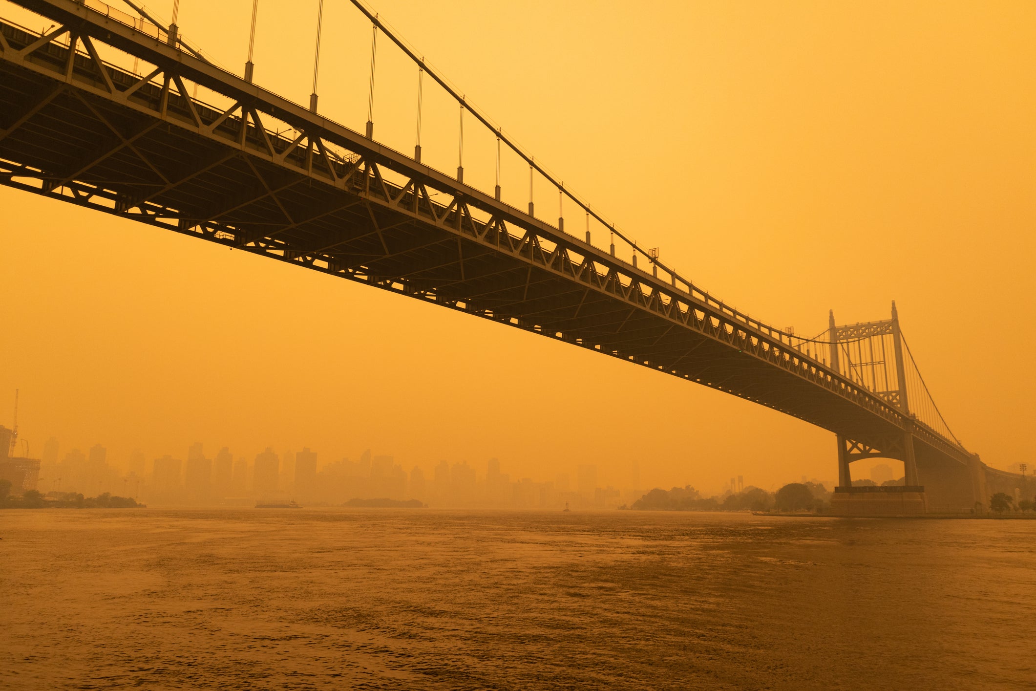 The Triborough Bridge along the East River in New York City with massive air pollution in the sky from wildfires.