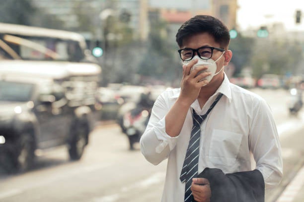 Business man wearing a mask on the street. Protection against air pollution and dust particles exceeds safety limits.PM2.5 unhealthy air pollution dust smoke in the urban city.